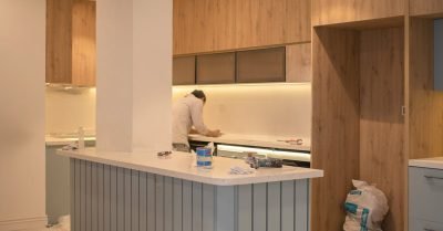 Contemporary kitchen undergoing renovation with wooden cabinets and clean design.