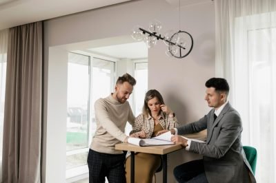 A couple consults with a real estate agent in a modern indoor setting, reviewing property documents.