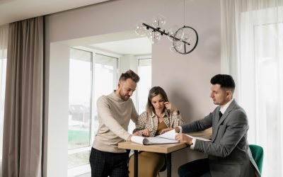 A couple consults with a real estate agent in a modern indoor setting, reviewing property documents.