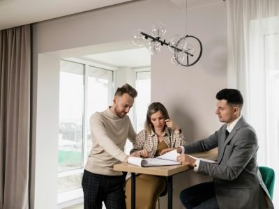 A couple consults with a real estate agent in a modern indoor setting, reviewing property documents.
